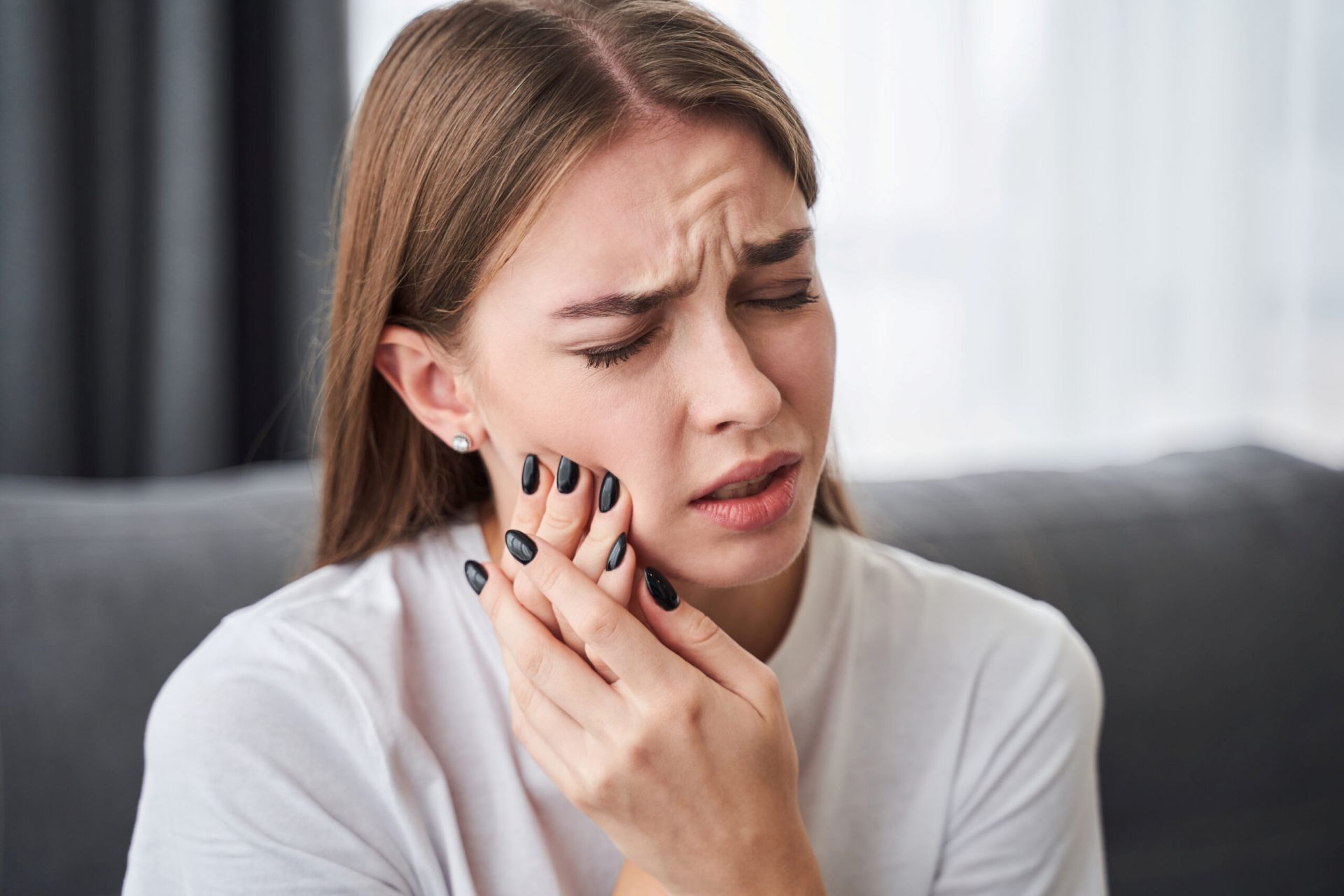 Woman holding her jaw in pain from a TMJ disorder