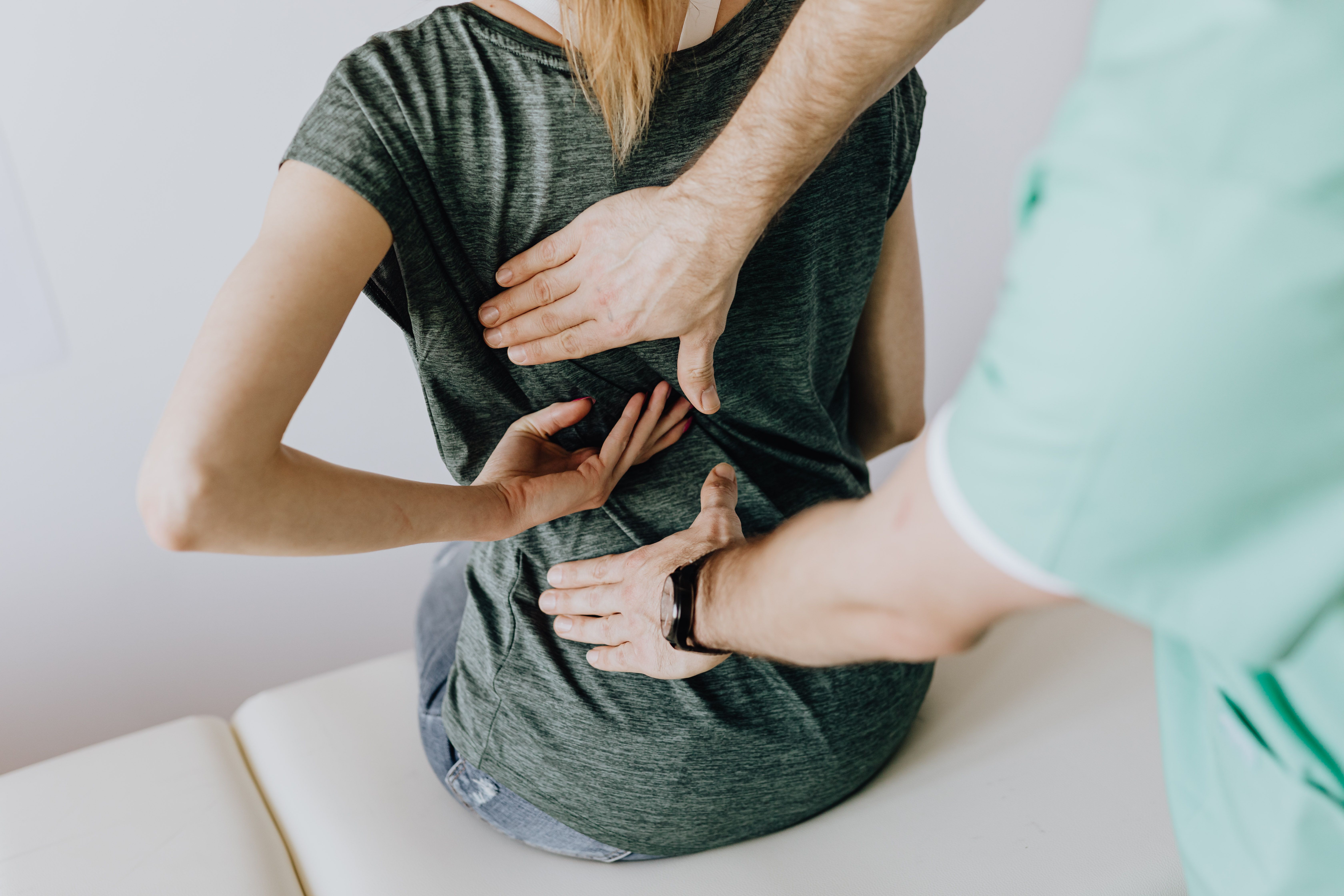 Physiotherapist assessing a patient's lower back for sciatica